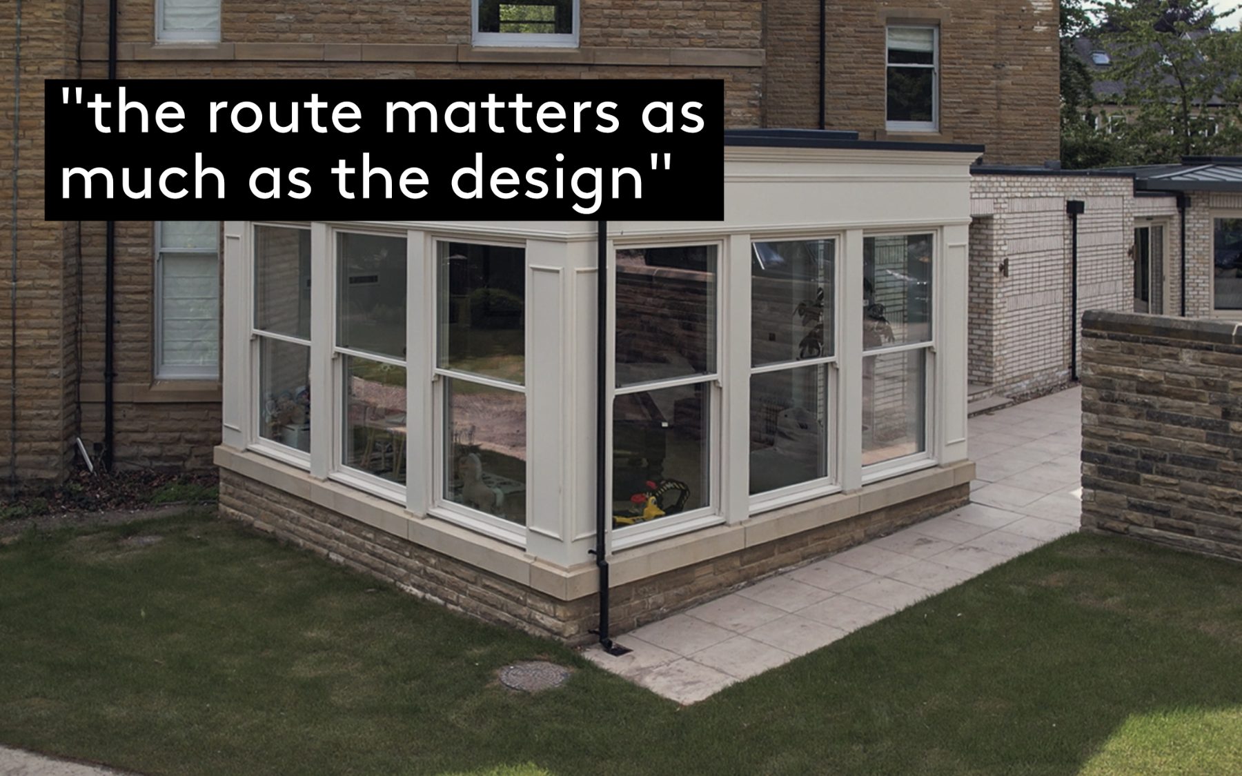 A painted timber garden room extension with slender glazing bars and a stone plinth, added to the rear of a Yorkshire stone house in Leeds